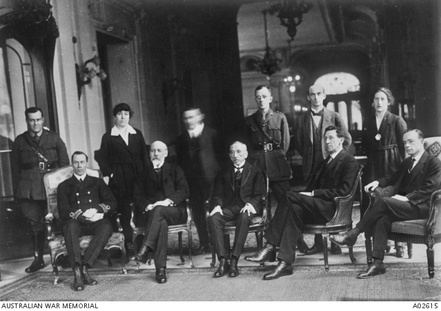 A black and white group portrait of nine men and two women with five people seated and six people standing. 