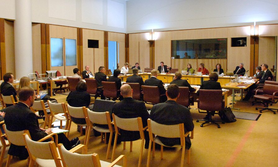 A Parliamentary committee in action at Australian Parliament House. Observers are watching the main discussion.