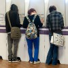 Slide 2: A photo of 3 people voting at a row of purple and white voting booths, with their backs to the camera.