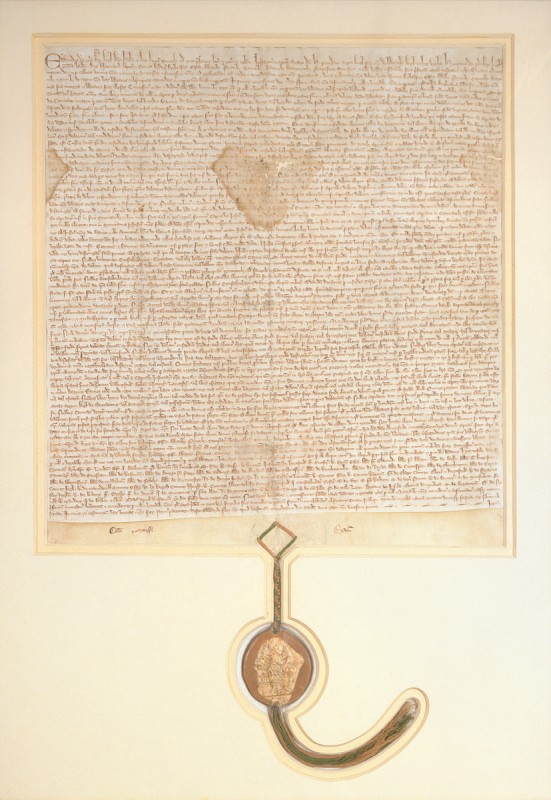 The 1297 Magna Carta. The rectangular document is covered in small, old-style writing. A seal hangs from the bottom.