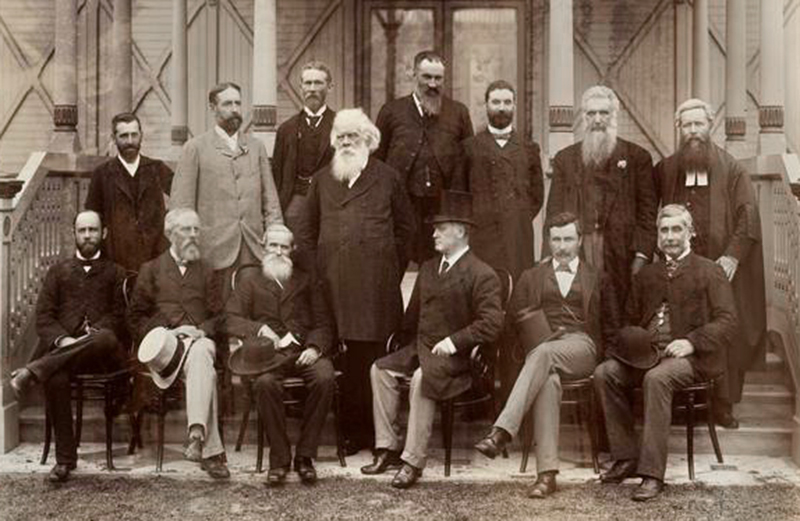 A sepia-toned formal portrait of a group of men in formal attire.