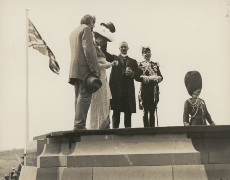 Lady Denman reads the name of the national capital. Prime Minister Fischer waves his hat in the air while the Governor-General and others look on.