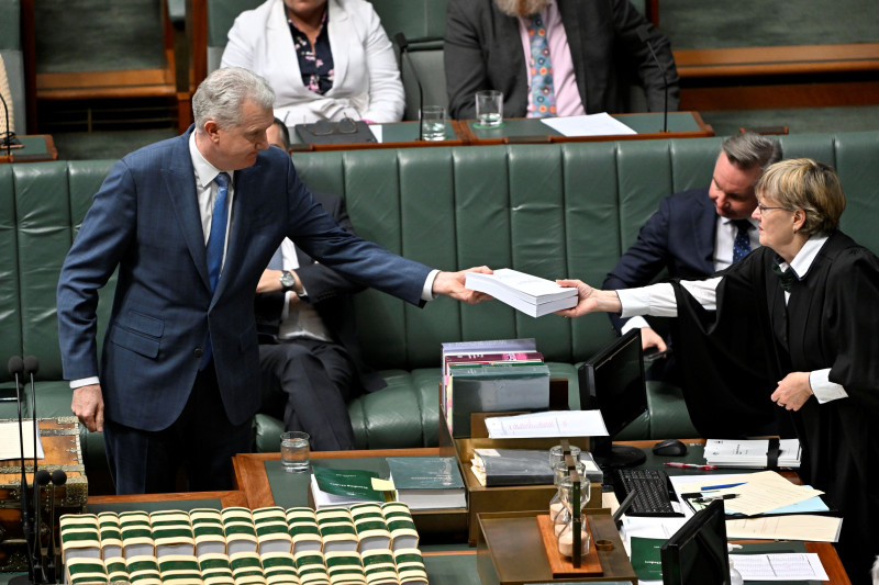 A minister handing a stack of documents to the Clerk in the House of Representatives.