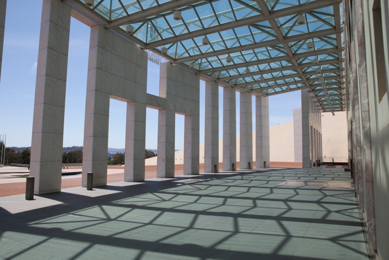 A large enclosed walkway, with shadows cast on the pavement.