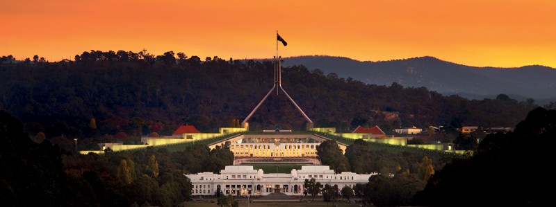 Provisional (Old) Parliament House in the foreground with Parliament House illuminated in the background.