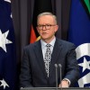 Slide 2: A man in a suit speaking into microphones at a lectern. Behind him is an Australian flag, an Aboriginal flag and a Torres Strait Islander flag.