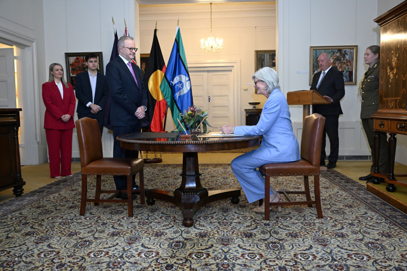 The Governor-General sits at a wooden desk with pens and paperwork. Anthony Albanese is standing at the desk to be sworn in as Prime Minister.