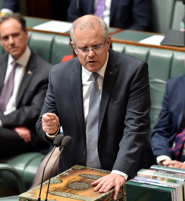 The Prime Minister speaking from the Despatch Box in the House of Representatives. Other members are sitting behind him.