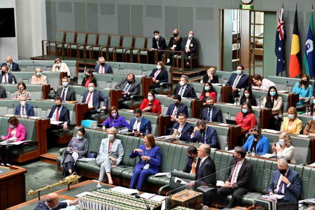 The House of Representatives with a large table at which the Prime Minister and the Clerks sit. There are 5 rows of seats behind the Prime Minister, with the rear 4 rows also having desks in front of the seats.