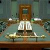 Slide 1: The Mace positioned on brackets on the central table in the green House of Representatives. There are books on the table.