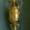 Slide 2: A detailed view of the gold Mace clearly showing the crown with its emblems and etchings. The Mace is standing upright. 
