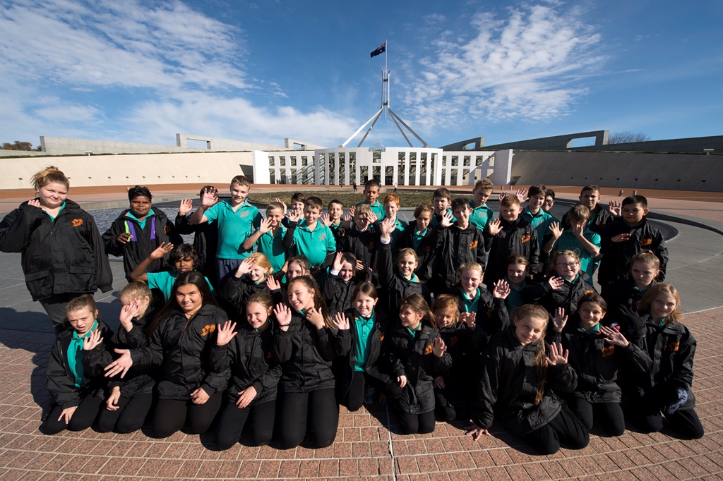 A group of students on a school trip in front of Australian Parliament House.